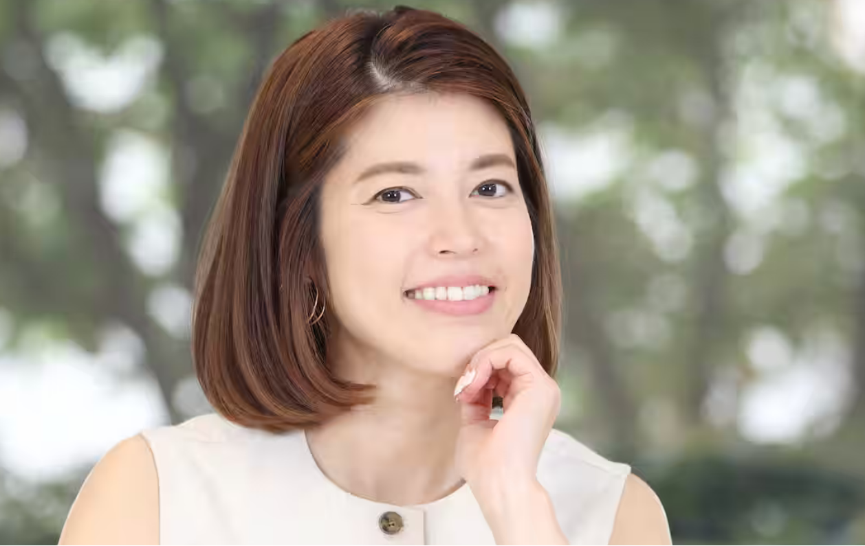 フリーアナウンサーの神田愛花さん。緑を背景に、顎に手を当てて穏やかな笑顔を見せているポートレート。